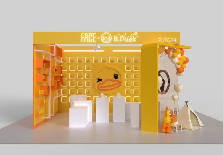 Yellow booth with a large winking duck face, product shelves, white pedestals, balloons, and a small tent.
