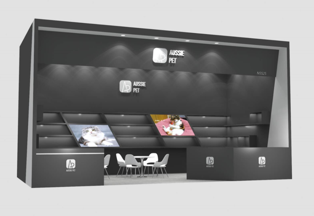 dark exhibition booth with screens displaying cats, shelves, white table and chairs.