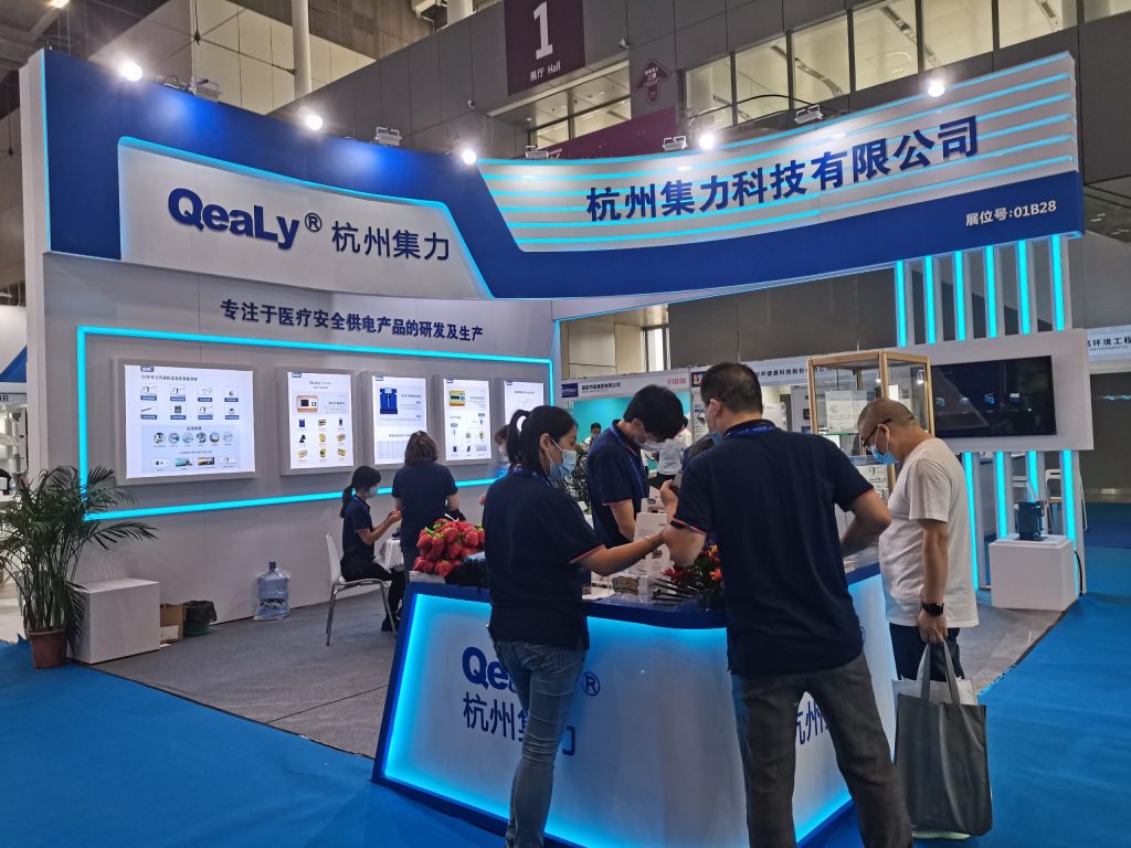 Busy trade show booth, people interact at a counter with glowing displays.
