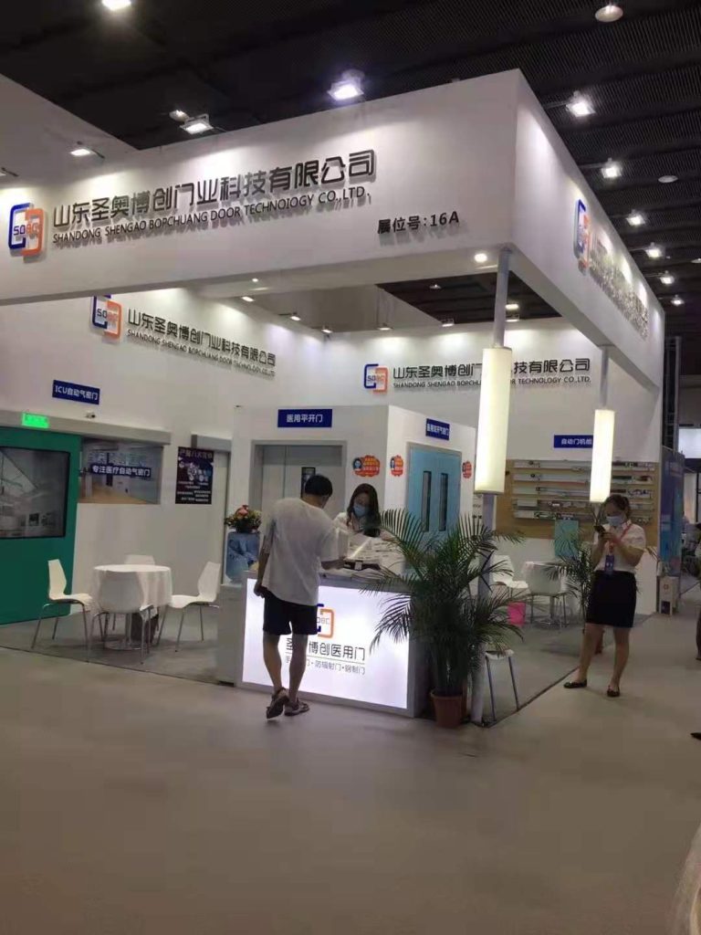 Trade show booth with people, modern doors, reception desk.