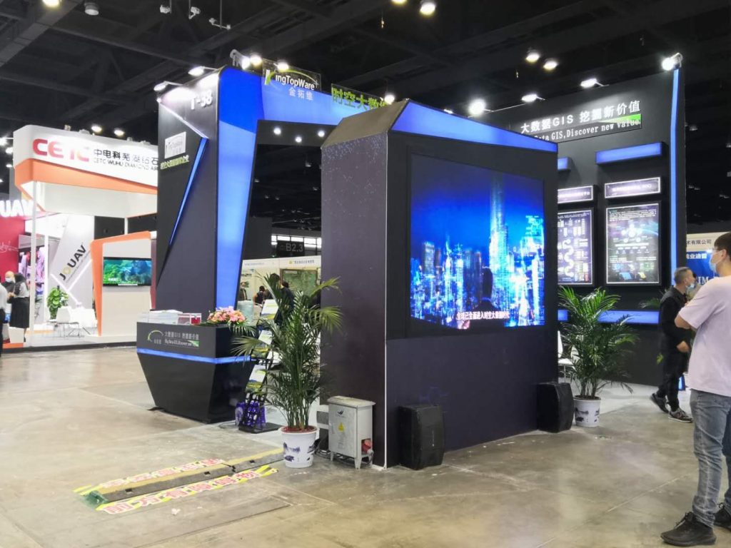 Booth, large cityscape screen, plants.