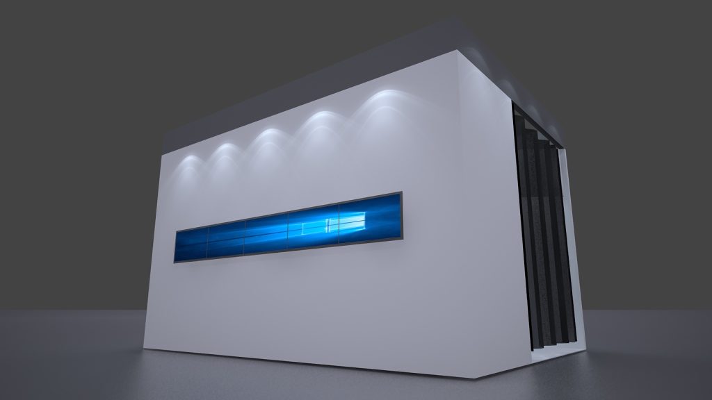 Modern white and grey display booth featuring a long, glowing blue screen on its front wall, lit by spotlights.