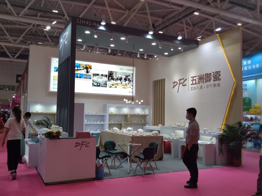 Real exhibition booth showcasing white ceramics, with people on a pink floor.