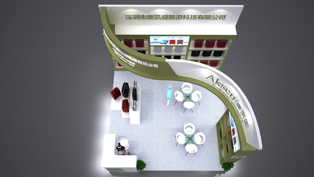 Overhead view of a green and white trade show booth render, showing shelves of suitcases, a reception desk, and two round tables with chairs on a patterned floor.