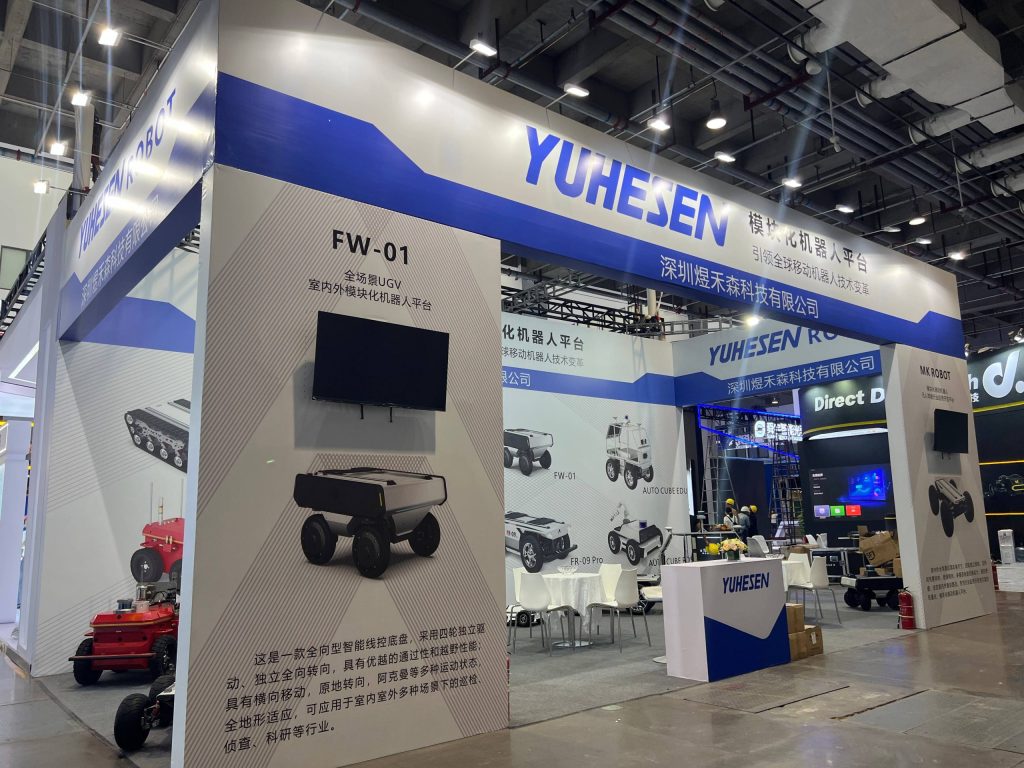 Expo booth featuring robotic vehicles on screen and floor.
