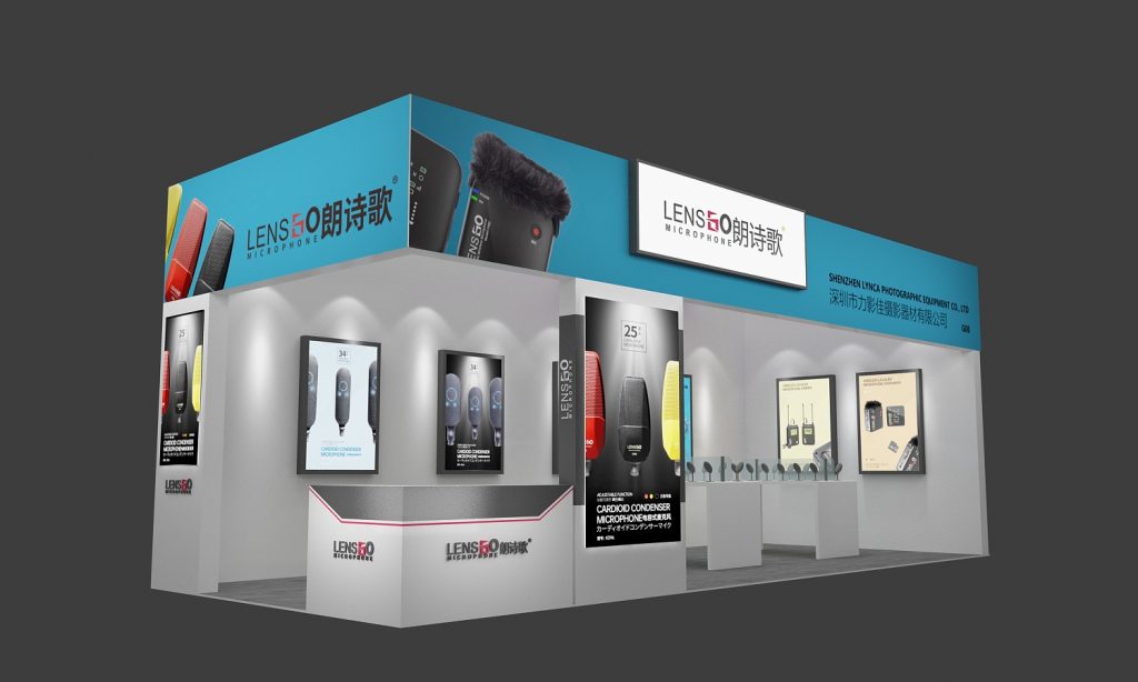 Angled view of an exhibition booth with blue and white branding, displaying various microphones on stands and in framed posters, with a reception desk.