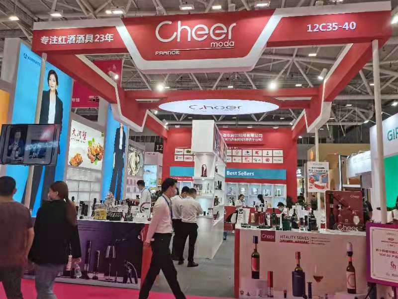 A bustling red and white trade show booth with products displayed, featuring interactive screens and several people exploring the exhibits.