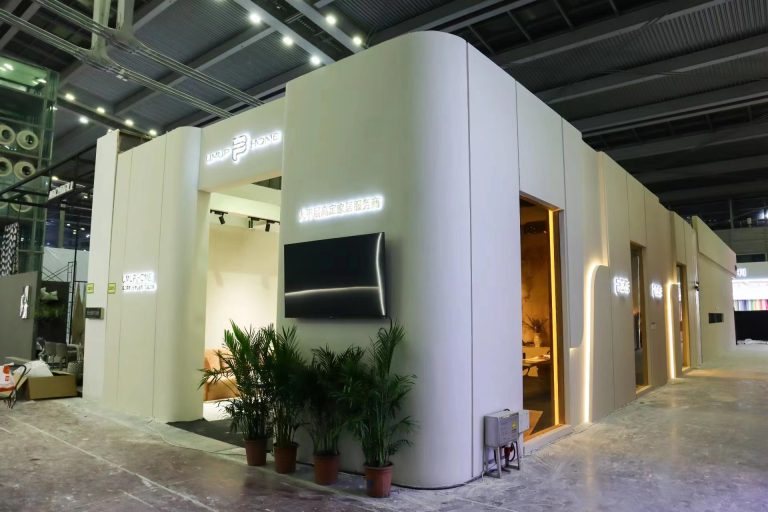 Exhibition booth exterior: glowing signs, plants, mounted screen.