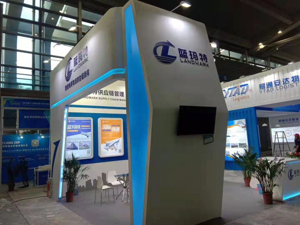 A white and blue exhibition booth with illuminated blue accents and a seating area.