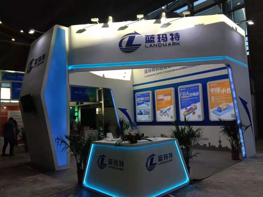 An exhibition booth with a blue and white design, a reception desk, and a wall display.