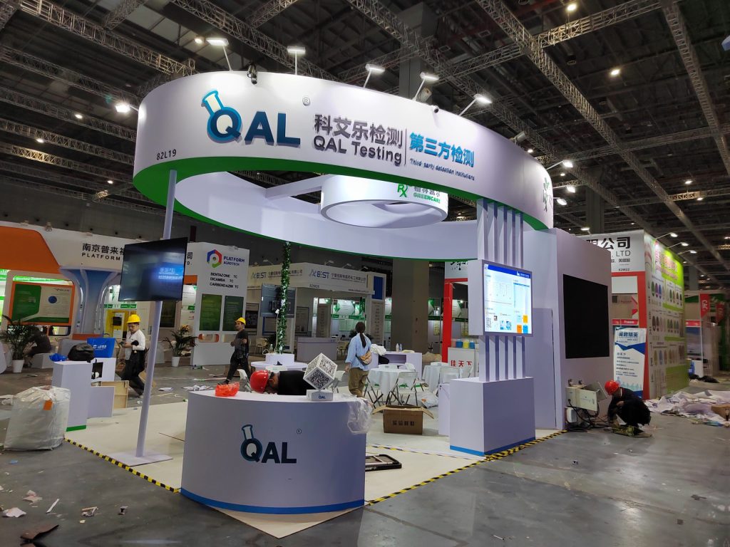 Exhibition booth under construction with workers and screens.