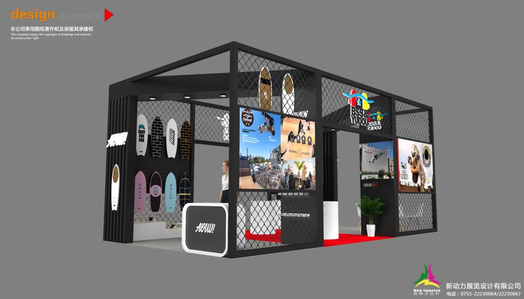 Interior view of a black trade show booth with surfboard displays, multiple video screens, a mannequin, and a white reception desk.