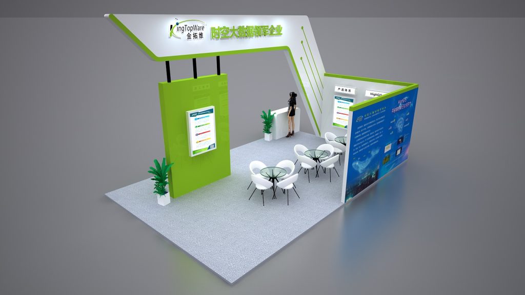 Aerial view of a modern green and white exhibition booth with an arched entrance, display panels, reception desk with a mannequin, and seating area.