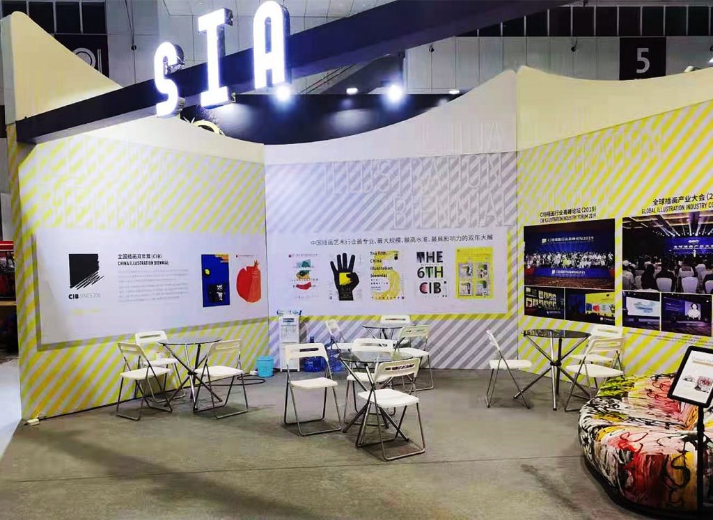 Exhibition booth with tables, chairs, and wall graphics.