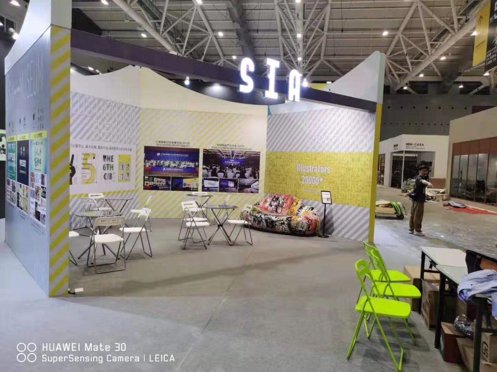 Booth with colorful sofa, tables, and green chairs nearby.