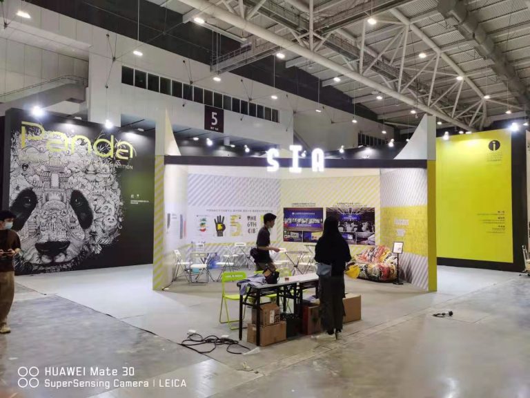 Exhibition hall, booth with people, and large panda art.