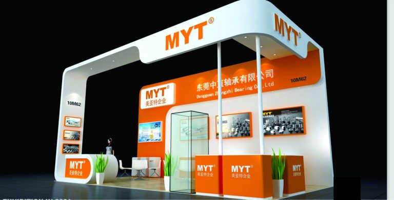 Modern white and orange exhibition booth with displays, reception, and seating.