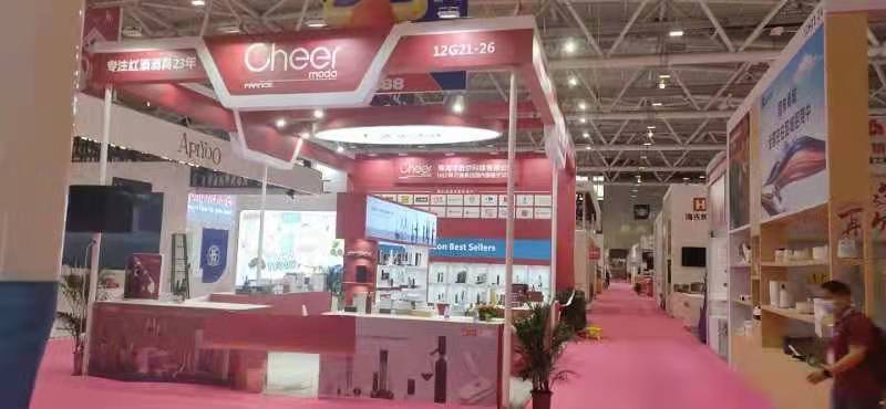 Real-world red and white trade show booth with product displays and signage, set on a pink carpet in a bustling exhibition hall.
