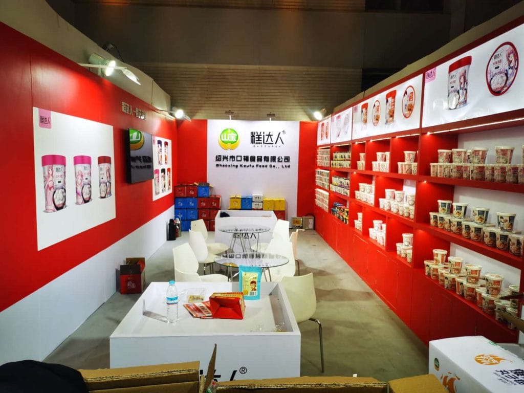Red and white exhibition booth fully stocked with packaged food products.
