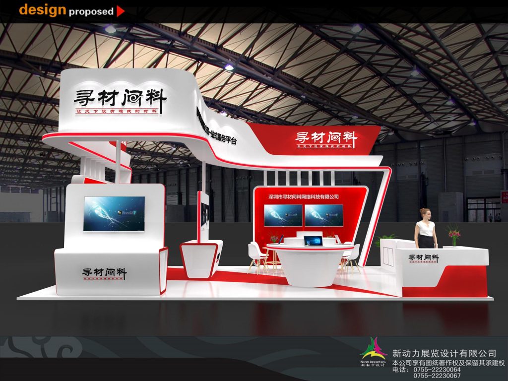 Modern red and white exhibition booth with several digital screens, counters, and seating areas. A woman stands at a counter on the right.