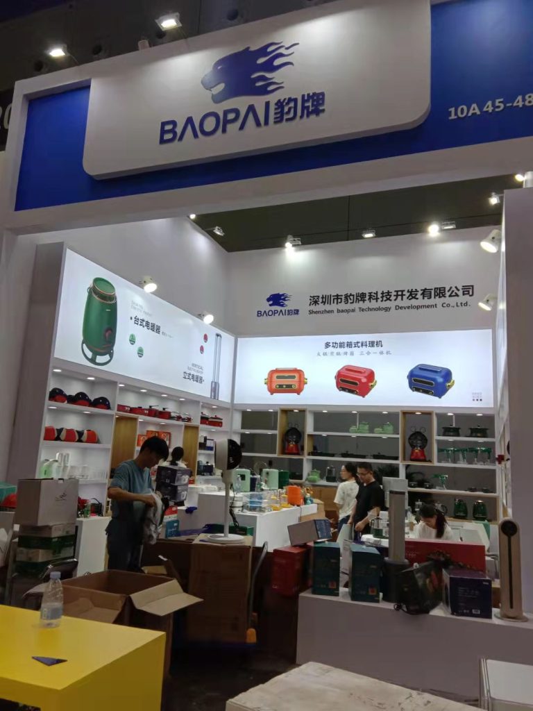 Busy exhibit booth with people, products, and boxes, showcasing appliances.
