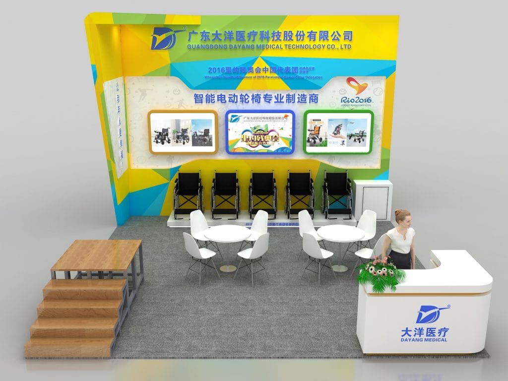 A 3D render of an exhibition booth featuring medical equipment, including wheelchairs on display, a reception desk, tables, and chairs, in a yellow and green design.