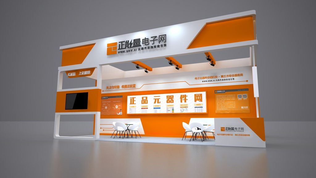 Render of an orange and white exhibition booth wall, featuring a large screen, several display panels showing components, and two small white tables with chairs.