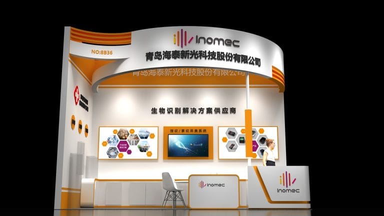 Render of a sleek white and orange exhibition booth with three display screens and a large monitor, next to a reception desk with a chair.