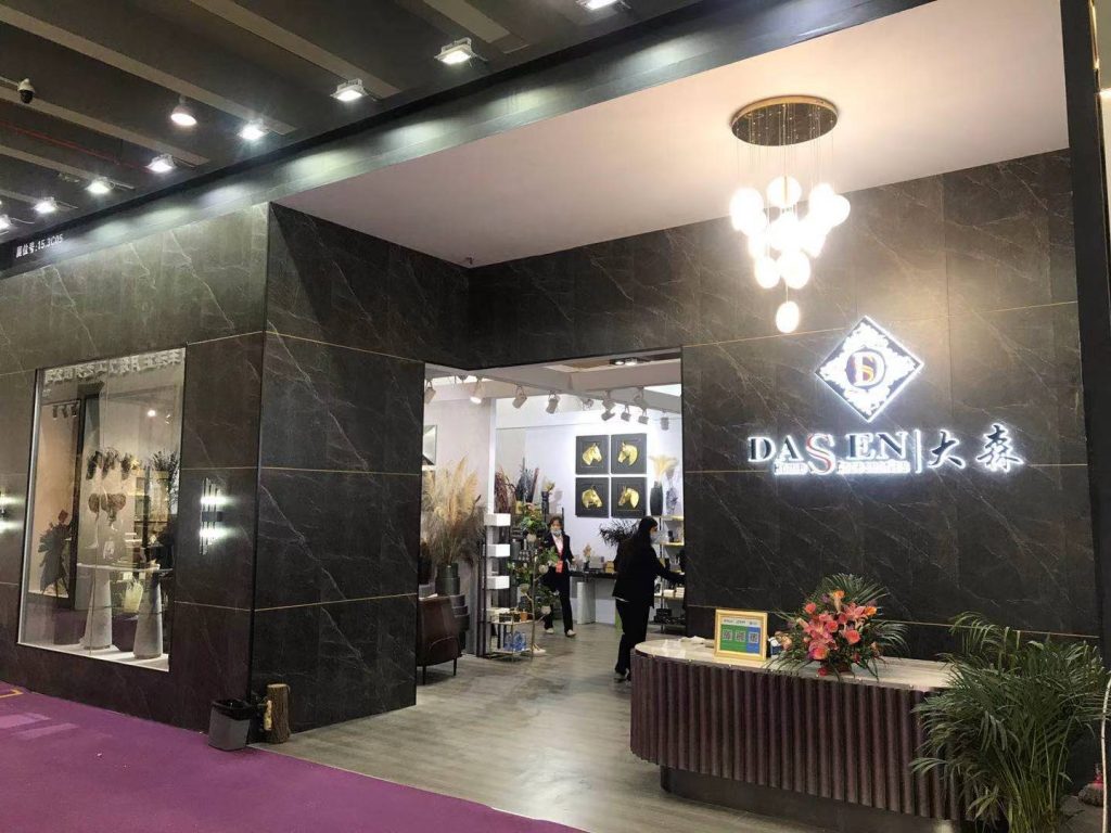 Real-world store entrance with dark marble facade, large doorway, ornate chandelier, and people inside. A floral arrangement sits on a front counter.