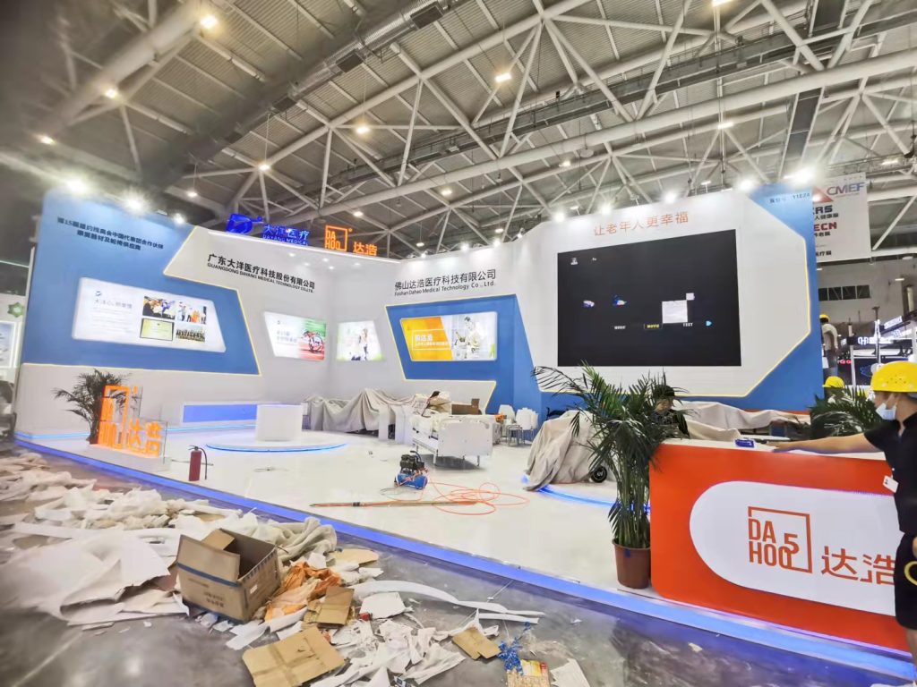 Exhibition booth under construction with debris on the floor and covered displays.