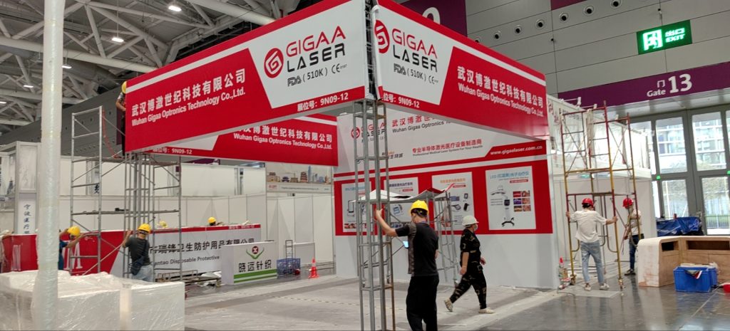 Exhibition booth frame under construction with workers and scaffolding.